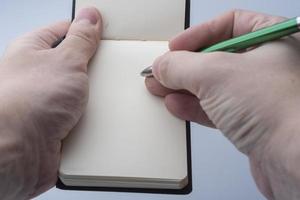 Hands of a man holding a notebook and a pen on a white background. photo