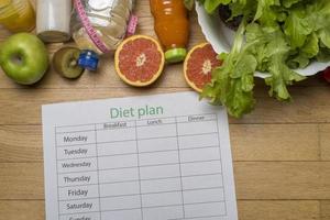 Diet plan, tape measure, water, diet of fresh fruits on the wooden floor. photo