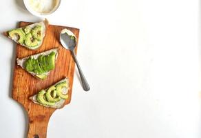 Avocado sandwiches with fish butter on a wooden stand on white background. photo