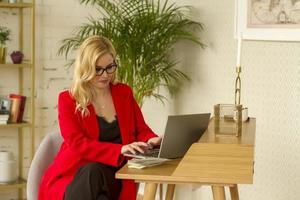 Beautiful blonde business lady working at home on a laptop. photo