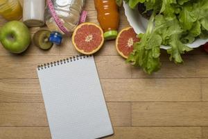 Diet plan, tape measure, water, diet of fresh fruits on the wooden floor. photo