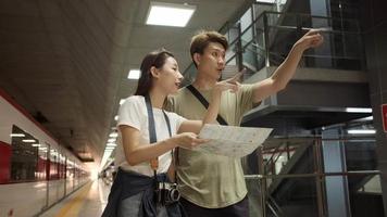 el hombre tailandés ayuda a una hermosa turista asiática a buscar información y encontrar un lugar para viajar en la plataforma de la estación de tren, estilo de vida de viaje de pasajeros, transporte informal en vacaciones de viaje. video