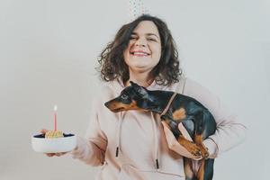 Happy young girl giving homemade cake to her dog, indoors photo