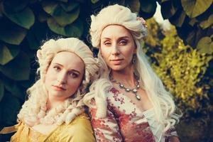retrato de dos mujeres rubias vestidas con ropa barroca histórica