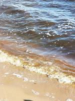 Close-up of the sandy shore of the lake.Foam on the water.Wet sand photo