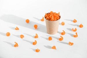 Orange pasta in a disposable kraft paper cup on a white background. Copy, empty space for text photo