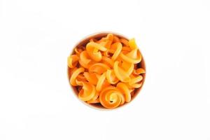 Orange pasta in a disposable kraft paper cup on a white background. Top view. Copy, empty space for text photo