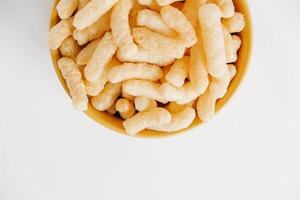 Corn sticks in a yellow bowl on a white background. Top view. Place for your text photo