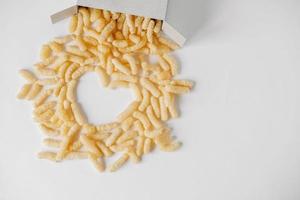 Corn sticks in paper box scattered heart shaped on a white background. Top view. Place for your text photo