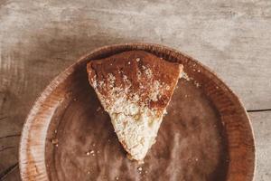 Piece of homemade apple pie in a paper plate on a wooden background. Top view. Copy, empty space for text photo