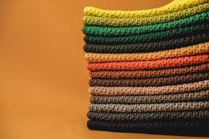 Stack of knitted material from multicolored threads on a orange background. Copy, empty space for text photo