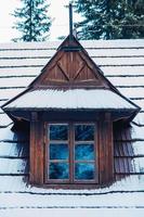 Window and roof of a wooden house covered with snow. Place for text or advertising photo