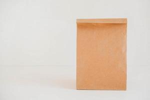 Closed disposable package made of brown kraft paper on a white background. Copy, empty space for text photo