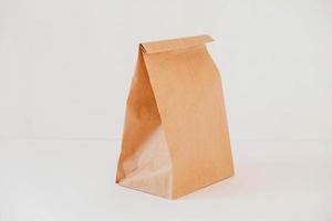 Closed disposable package made of brown kraft paper on a white background. Copy, empty space for text photo