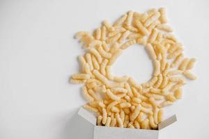 Corn sticks in paper box scattered heart shaped on a white background. Top view. Place for your text photo