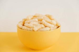 Corn sticks in a yellow bowl on a yellow background. Copy, empty space for text photo
