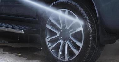 neblina de agua después de rociar las ruedas del coche para lavar. se esparció agua al automóvil mientras se rociaba. concepto de coche video
