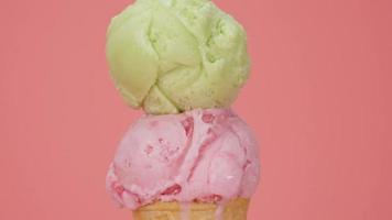 time lapse, scioglimento di shetbet e gelato alla fragola sul cono. il gelato fuoriesce lentamente dal cono. sullo sfondo rosa. video
