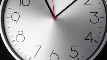 Silberne Wanduhr zeigt die Zeit an. Rotation der kurzen und langen Zeiger der Uhr. auf dem schwarzen Hintergrund. video