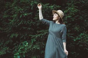 Woman in a straw hat and dress on a background of green forest and trees. Place for text or advertising photo