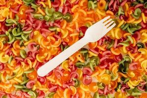 Multicolored pasta with a wooden fork as a background image. Top view. Copy, empty space for text photo