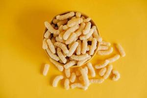 Corn sticks in a yellow bowl on a yellow background. Top view. Place for your text photo