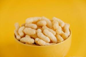 Corn sticks in a yellow bowl on a yellow background. Copy, empty space for text photo