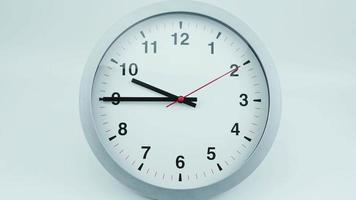 lapso de tiempo, el reloj de pared blanco indica la hora de las diez. rotación de las manecillas cortas y largas del reloj. sobre el fondo blanco. video