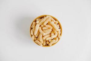 Corn sticks in a yellow bowl on a white background. Top view. Place for your text photo