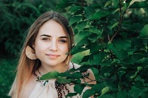 retrato de una hermosa chica rubia con belleza natural en árboles de hojas verdes. copiar, espacio vacío para texto foto