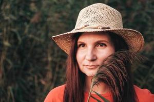 Portrait of a beautiful woman in a straw hat and dressed in red clothes on a background of reeds photo