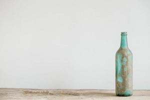 botella de vidrio vacía en la suciedad sobre una mesa de madera. copiar, espacio vacío para texto foto