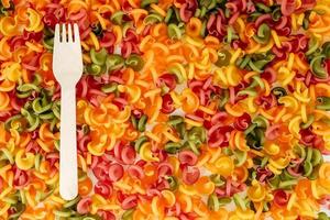 Multicolored pasta with a wooden fork as a background image. Top view. Copy, empty space for text photo