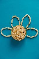 Corn sticks in a bowl in the shape of a flower on a blue background. Top view. Place for your text photo