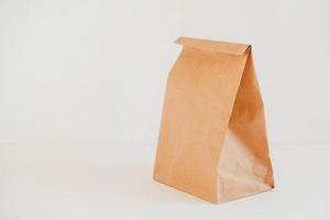 Closed disposable package made of brown kraft paper on a white background. Copy, empty space for text photo