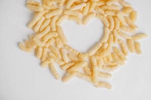 Corn sticks scattered heart shaped on a white background. Top view. Place for your text photo