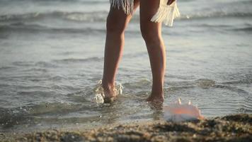 primer plano de las piernas de una mujer caminando en un agua de mar en una puesta de sol video