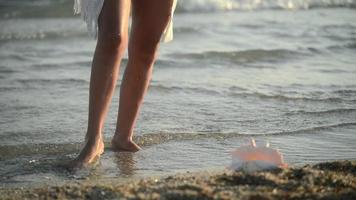 Nahaufnahme der Beine einer Frau, die bei einem Sonnenuntergang auf einem Meerwasser tanzen
