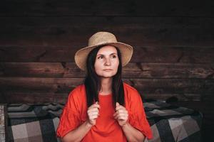 Portrait of a beautiful woman in a straw hat dressed in red clothes on background of a wooden wall photo