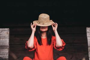 Portrait of a beautiful woman in a straw hat dressed in red clothes on background of a wooden wall photo