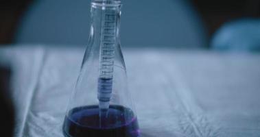 wissenschaftler gaben eine violette flüssigkeit in einen konischen kolben in einem labor, zeitlupe, verfolgen video