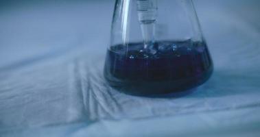bulles sortant d'une pipette graduée dans une fiole conique dans un laboratoire.