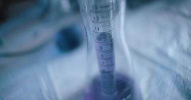 scientifique sortant un liquide violet d'une fiole conique dans un laboratoire, travelling video