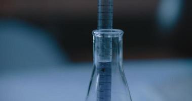 Scientist put a purple liquid into a conical flask in a lab,slow motion,tracking video