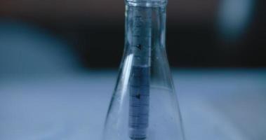 Scientist taking out a purple liquid from a conical flask in a lab,tracking shot video