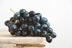 un racimo de uvas negras recién recogidas en una mesa de madera antigua. copiar, espacio vacío para texto foto