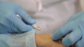 siringa per iniezione con ago di botox sotto la pelle della mano della donna, procedura di serraggio video