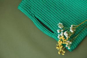 Stylish woman's knitted green bag on green background. Top view. Copy, empty space for text photo