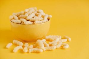 Corn sticks in a yellow bowl on a yellow background. Copy, empty space for text photo