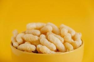 Corn sticks in a yellow bowl on a yellow background. Copy, empty space for text photo